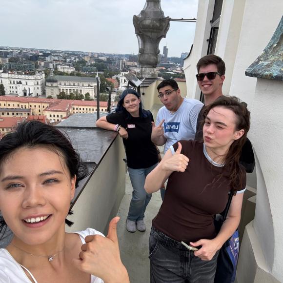 Males and females are standing on a top of a building