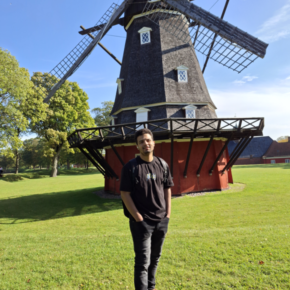 A male is standing in front of a windmill