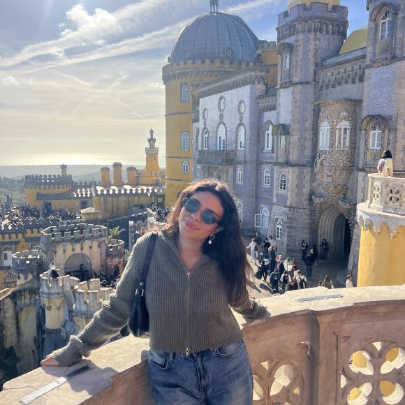 A female is leaning on a ledge with a wide view of buildings behind her